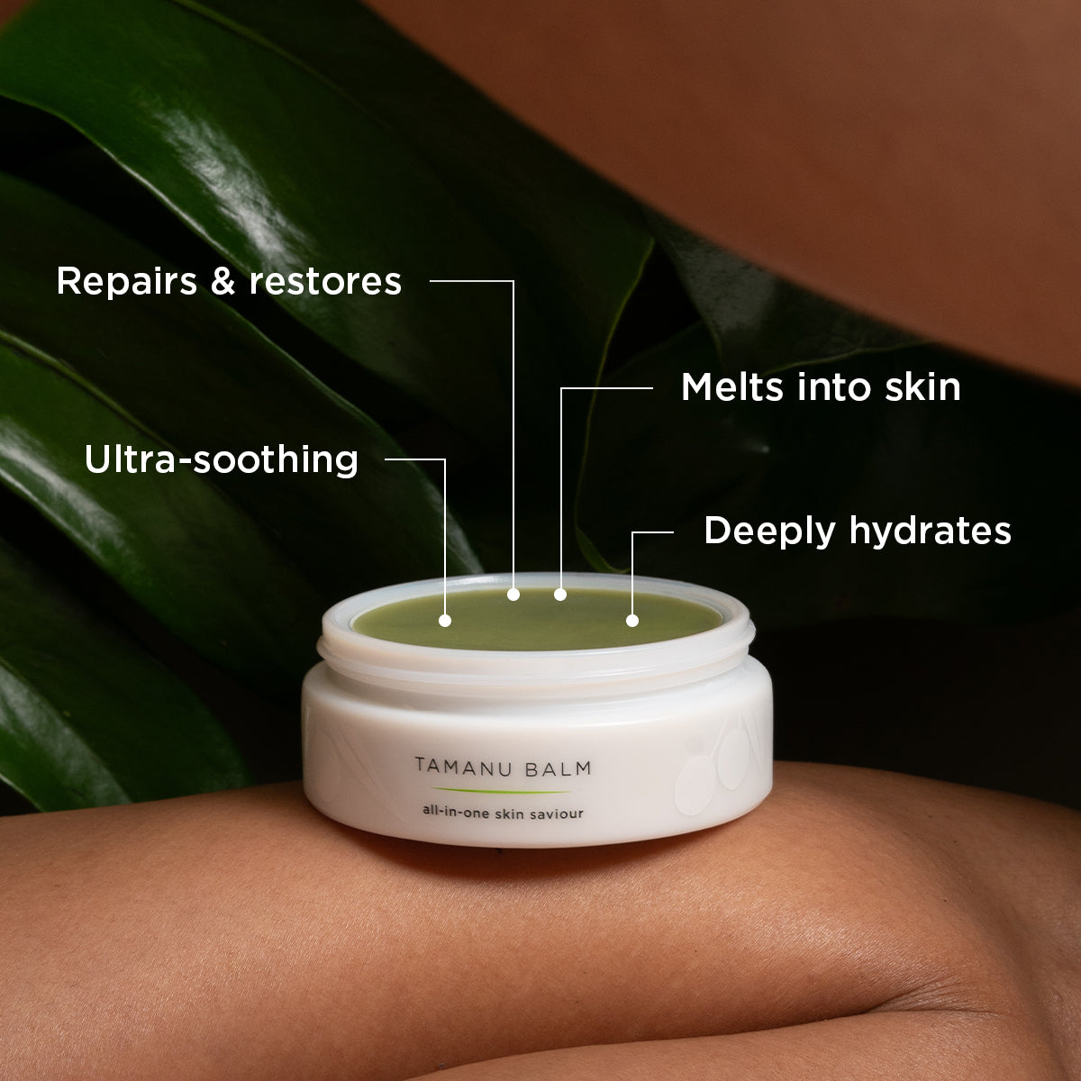 A container of Tamanu Balm, described as an "all-in-one skin saviour," is resting on a person's leg with a green leafy background. Text labels surrounding the balm highlight its benefits: "Repairs & restores," "Melts into skin," "Deeply hydrates," and "Ultra-soothing."